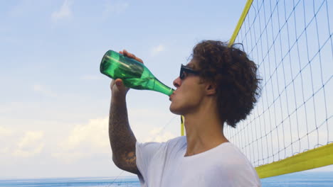 un joven bebiendo en la playa.