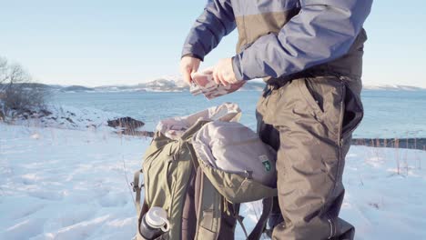 excursionista desenroscando una pala plegable portátil para cavar en un soleado día de invierno