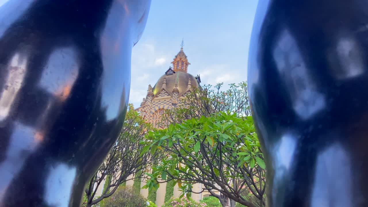 edificio principal de la plaza de fernando botero a través de las piernas de su escultura en medellín, colombia