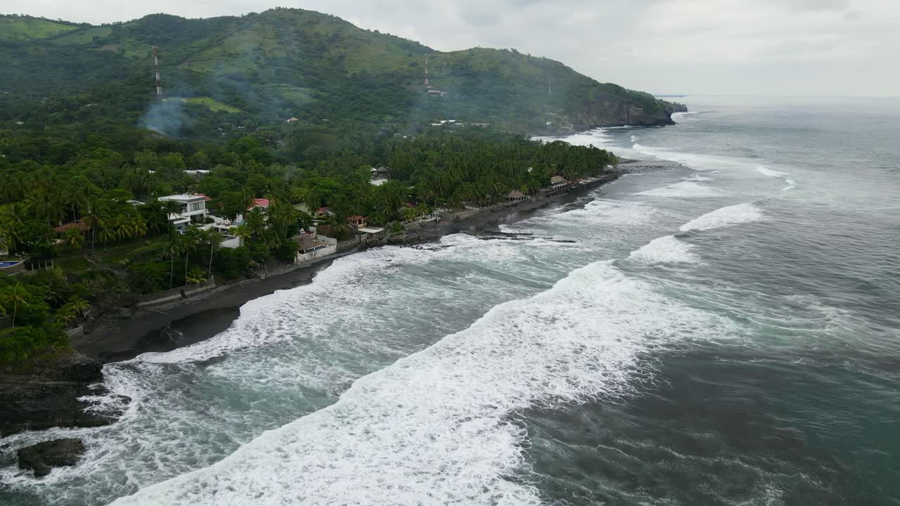 Aerial view moving forward shot, scenic view of the bitcoin beach in El Salvador, Mexico, houses and trees in the background