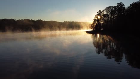 Sunrise-over-a-lack-as-a-drone-flies-through-mist