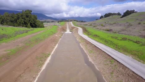 Good-vista-aérea-shot-of-an-aqueduct-flowing-through-the-desert-and-mountains-of-California-3