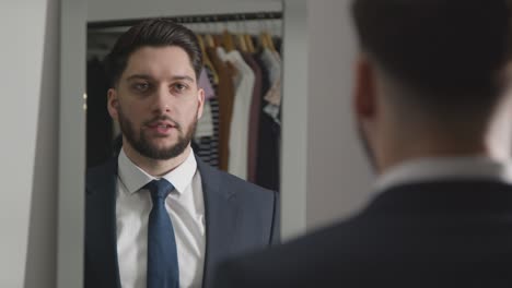 joven con traje en casa practicando la técnica de la entrevista de trabajo reflejada en el espejo 2