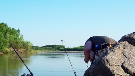 man with two fishing rods preparing his fishing lures standing on the banks of siret river in galati country, romania