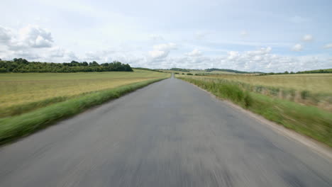 Vista-Exterior-Desde-La-Parte-Delantera-Del-Coche-Que-Viaja-Por-Una-Carretera-Rural