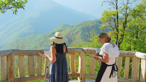 two artists painting a mountain landscape