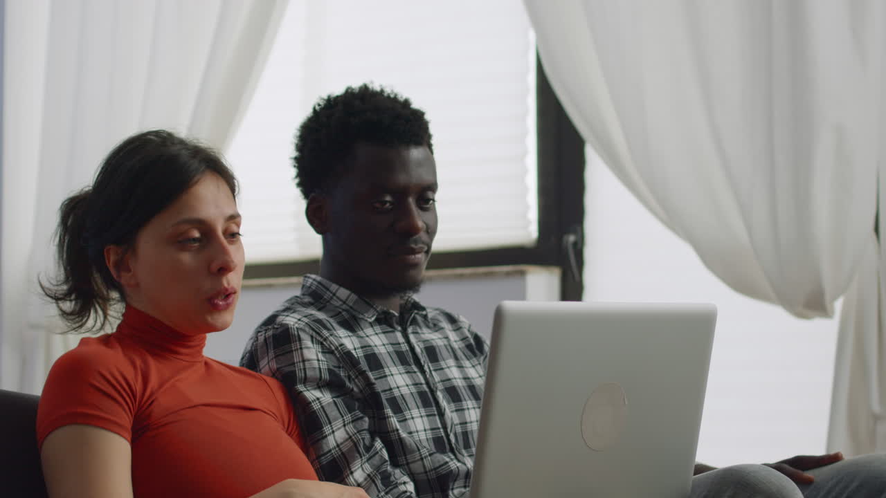 Young interracial couple talking on video call conference
