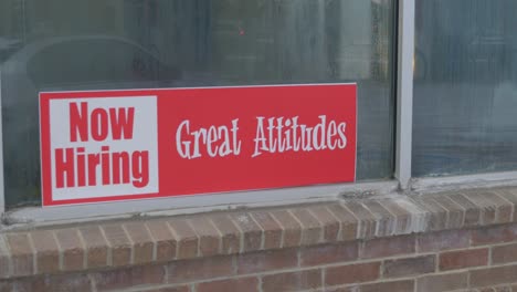 now hiring great attitudes bright red and white sign in window of car wash with condensation and dew on glass, reflection of cars and people, slow pan to right in cinema 4k 30fps slowed from 60fps