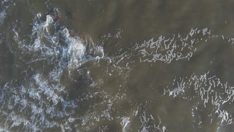 Top-view-of-waves-crashing-onto-the-rocky-shore