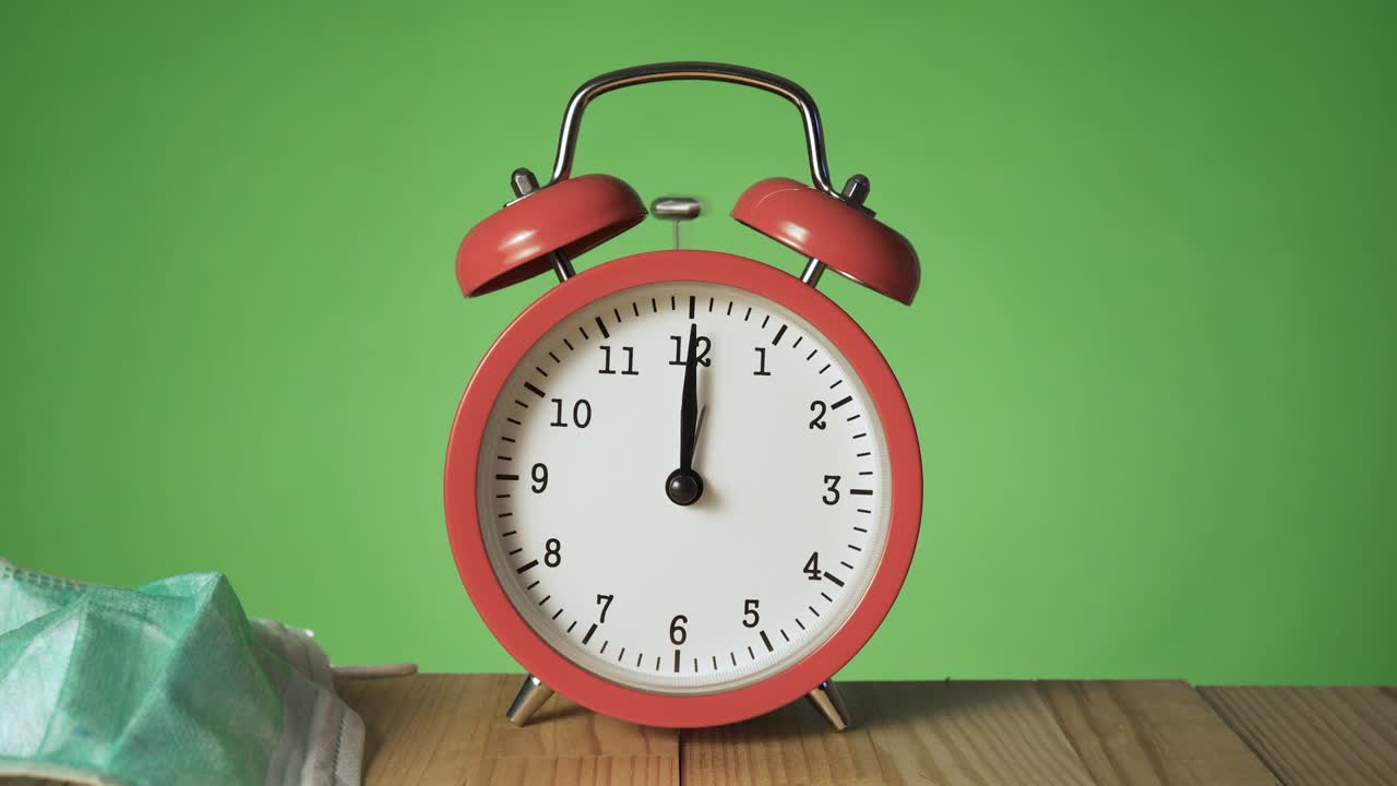 보호용 얼굴 마스크와 장갑은 12시에 울리는 천연 나무 테이블 위에 있는 옛날의 빨간 알람 시계에 던져졌다.