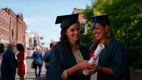 two graduates embracing with diploma on graduation day