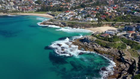 vista aérea de las olas rompiendo en tamarama y bronte beach en verano con suburbio costero en sydney, nsw, australia