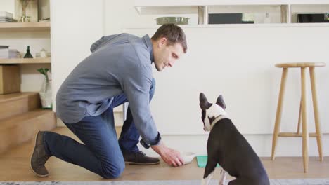 Happy-caucasian-man-training-and-feeding-his-dog-at-home