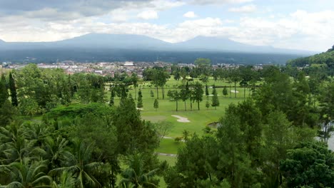 City-outskirts,-tropical-nature-and-mountains-in-Indonesia,-aerial-drone-fly-forward