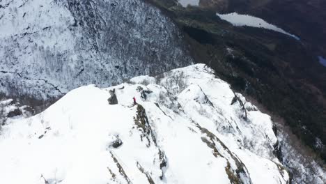 Toma-Aérea-Hacia-Una-Sola-Persona-En-La-Cima-De-Una-Montaña-Noruega-Helada