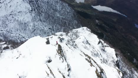 aerial shot towards single person on top of icy norwegian mountain