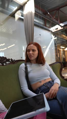 dos mujeres en conversación en un sofá en una oficina moderna