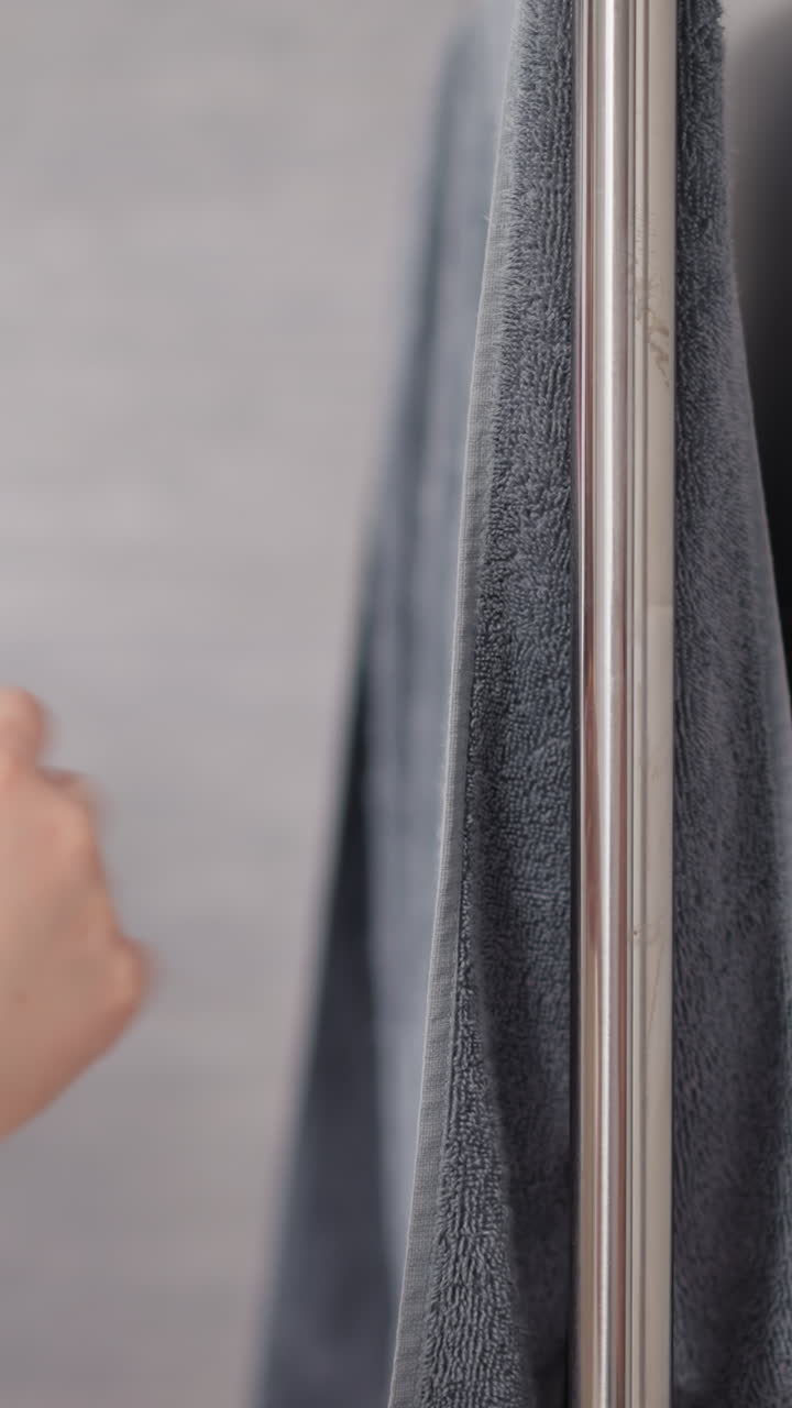 mujer con manicura se seca la mano con una toalla de baño después de ducharse. persona se seca la manos con una toallas colgada en la barandilla en la ducha en cámara lenta