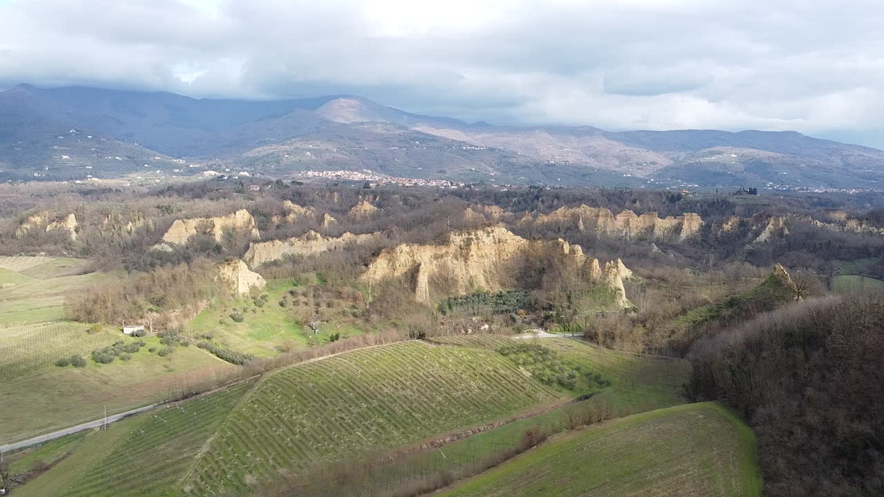 Orbiting next to prehistoric age canyons Le Balze natural reserve near Reggello. Tuscany, Chianti area. Italy. Winter season, partially sunny sunset