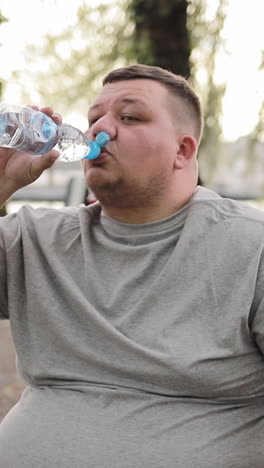 a fat man drinks water while exercising outdoors overweight man weight loss concept a fat man drinks water while exercising outdoors overweight man weight loss concept