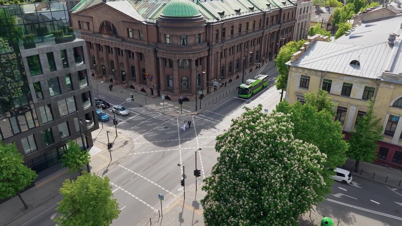 Riprese con drone catturano la Banca di Lituania a Kaunas, mostrando la sua grandiosa architettura, i viali alberati, gli edifici in vetro nelle vicinanze e gli incroci urbani soleggiati e tranquilli visti dall'alto.