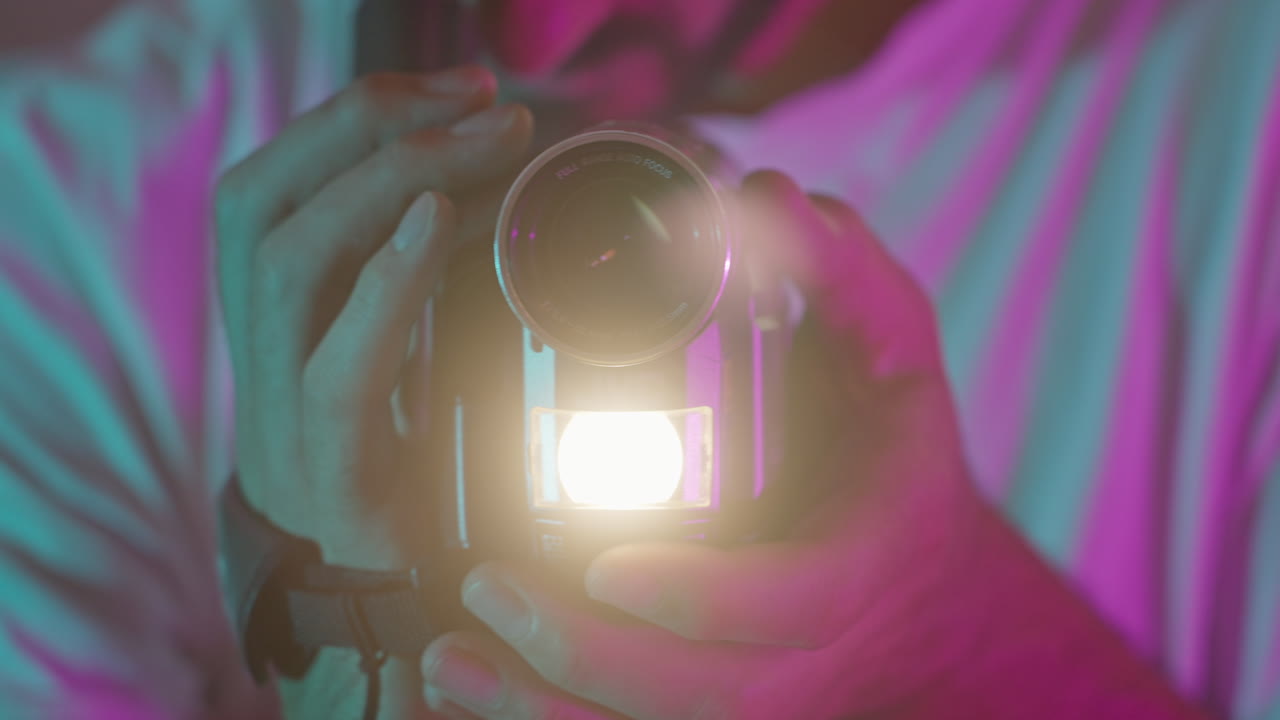 Pessoa Segurando Câmera de Vídeo Vintage com Luz Piscando em Cenário Neon