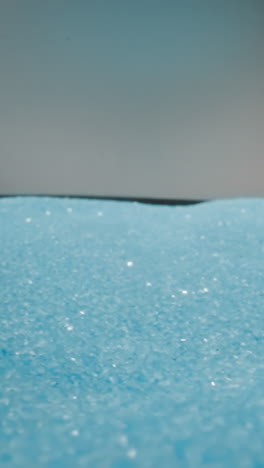 Shiny light blue sand shuddering from jolts on grey background. Tiny particles of sand glittering and shimmering at bright studio light macro