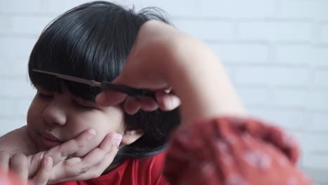 mother giving a haircut to a little girl