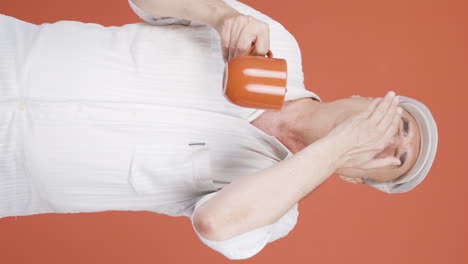 Vertical video of The old man&#039;s mouth is burning from the hot drink.