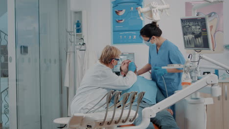 dentist and nurse examining teeth of patient in dentistry cabinet