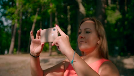 mujer caucásica sosteniendo un teléfono inteligente móvil tomando una foto en el bosque