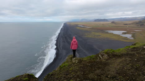 Erhebt-Sich-Auf-Eine-Frau,-Die-über-Einer-Klippe-Am-Aussichtspunkt-Dyrholaey-In-Island-Steht