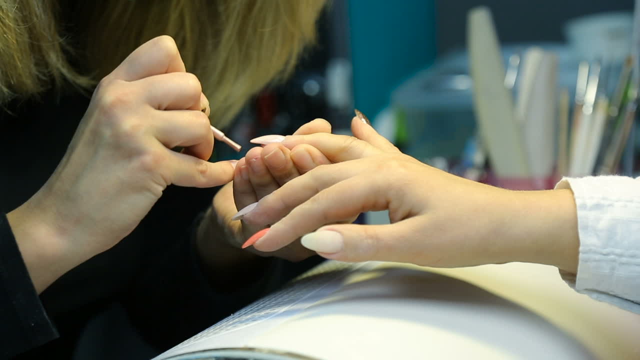 Woman in salon receiving manicure by nail beautician