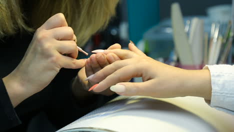 woman in salon receiving manicure by nail beautician
