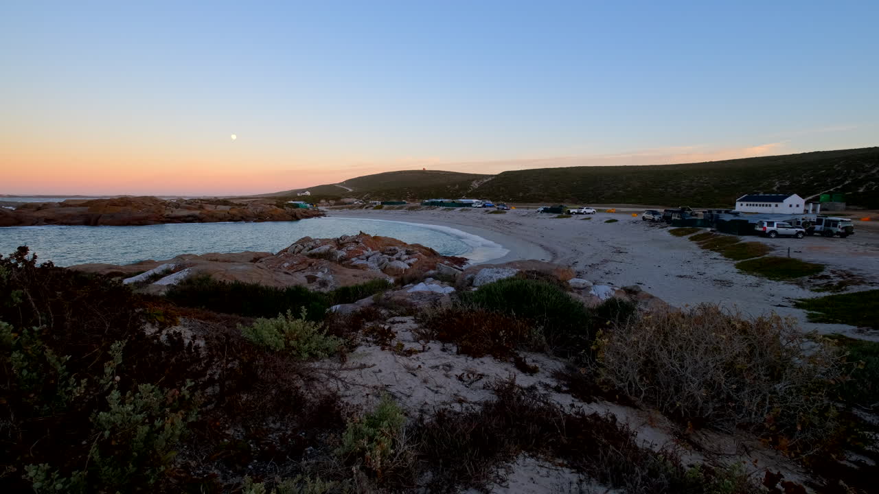 Udsigt til månedgang på en levende solopgangshimmel over Tietiesbaai campingplads på Kap Vestkysten