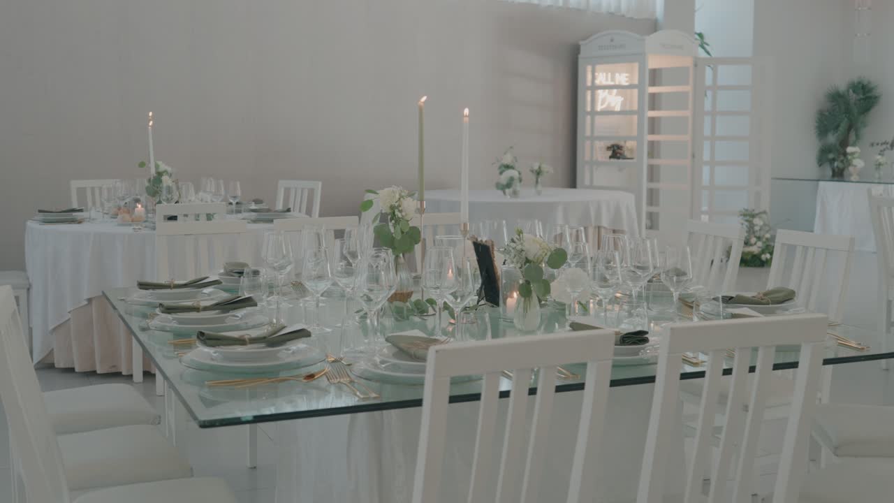 Mesas de banquete blancas con copas, velas y centros de mesa florales