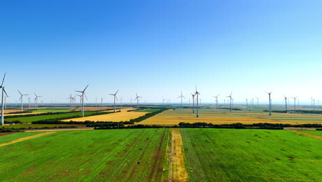 turbines rise in green fields. wind turbines rotate above lush green fields under a clear blue sky, illustrating sustainable energy in a rural area