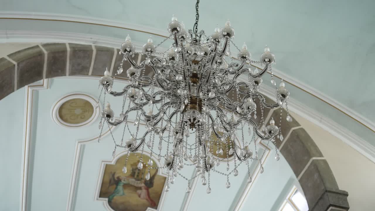 intricate crystal chandelier with ceiling artwork in church interior