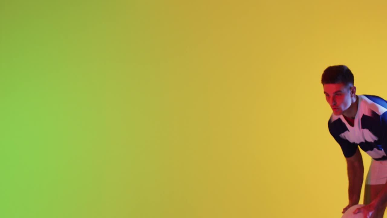 jugador de rugby masculino caucásico saltando con una pelota de rugby sobre la iluminación amarilla