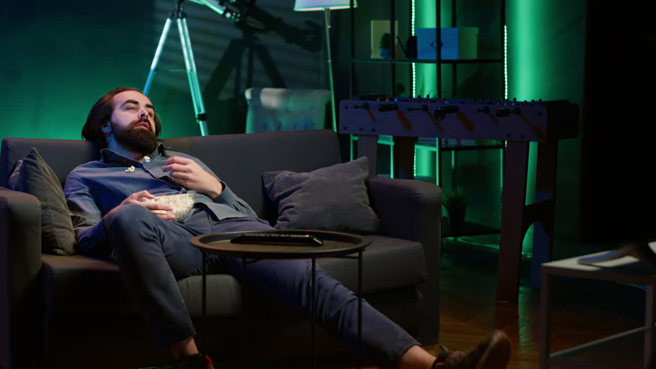 지루한 남자가 집에 가서 팝콘을 공중으로 던지며 자신을 즐겁게 하고 있습니다.