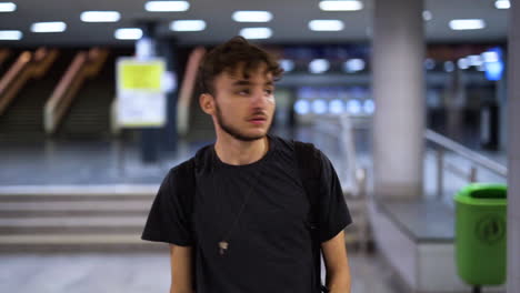 man walking through subway terminal alone, turning to check something behind him