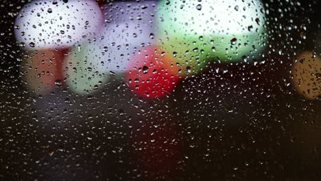 night city traffic through the wet car window. abstract bokeh lights of passing cars. rainy autumn weather. slow motion 4k