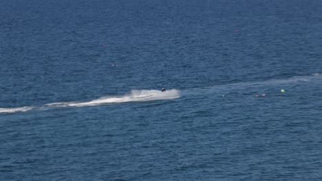 Hand-held-tracking-shot-of-a-jet-skier-racing-along-the-flat-sea-towards-Newquay-Harbour