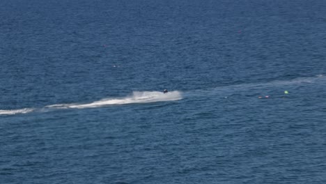 hand-held tracking shot of a jet skier racing along the flat sea towards newquay harbour