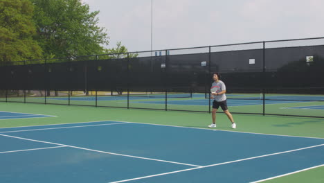 adult man using full strength hitting the ball with tennis racket, playing on tennis court in indianapolis, united states