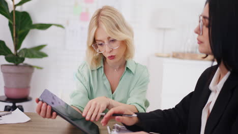 two women analyze financial report during business meeting