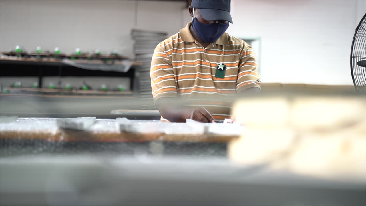 Man working at table of repair shop. Very focused on what his hands are doing. Slow motion.
