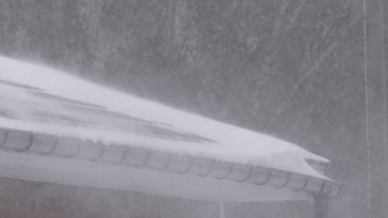 겨울 핀란드의 옥상에서 소용돌이치는 눈의 정적 보기를 닫습니다.