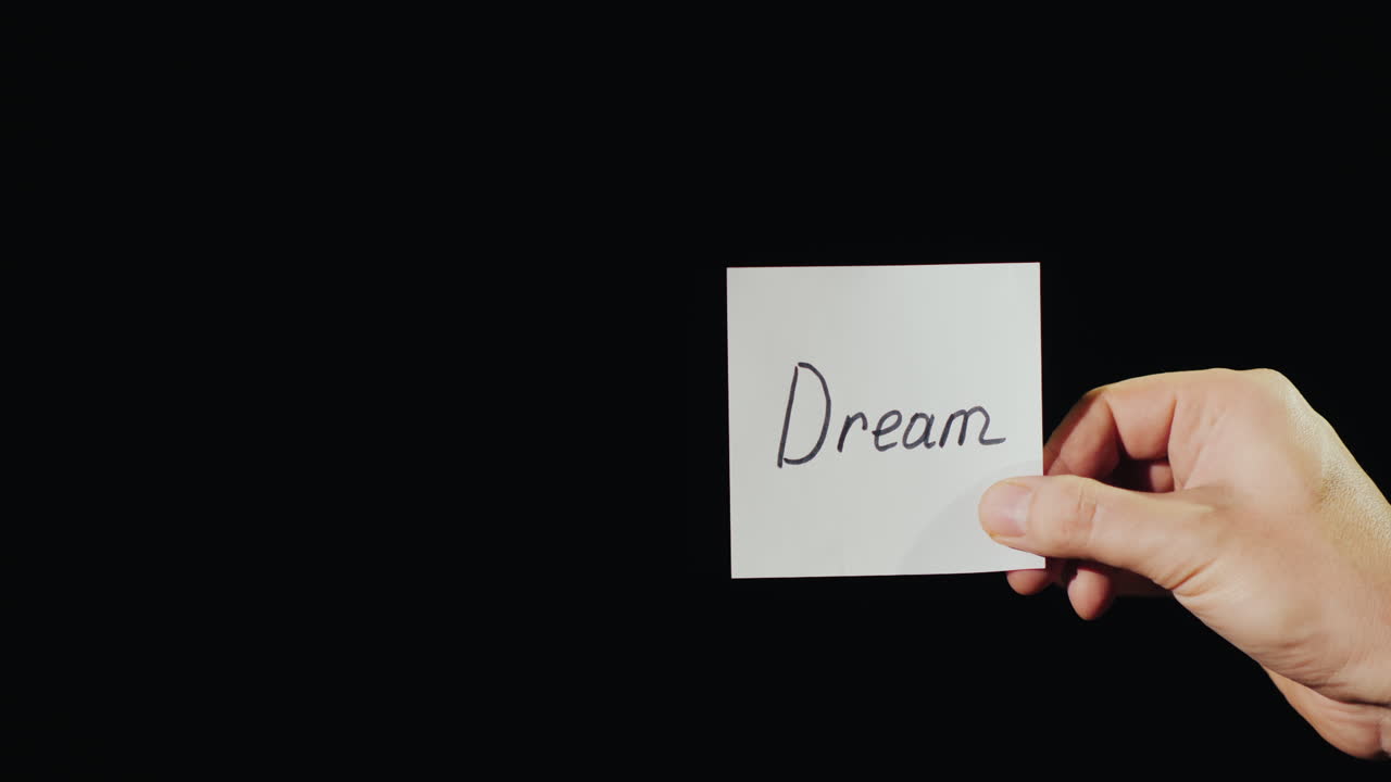 ruka drží hořící papír s nápisem sen