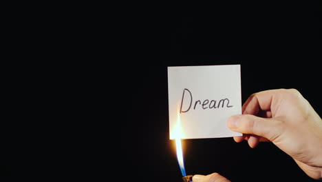 hand holds burning paper with inscription dream